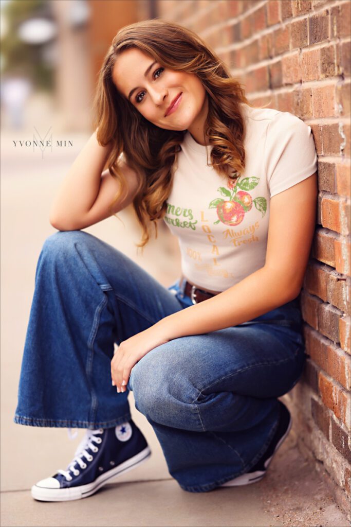 A high school senior picture of a student from Legacy High School posing against a wall in downtown Louisville, Colorado with Yvonne Min Photography.