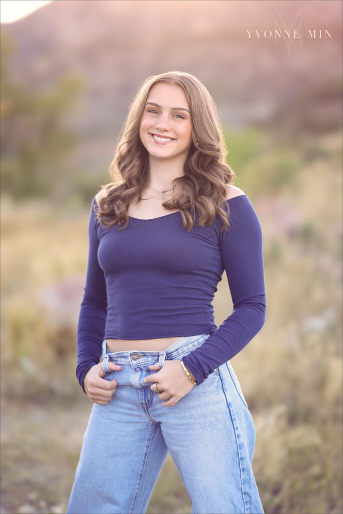A senior girl from Legacy High School poses in a field at her senior photoshoot with Yvonne Min Photography at South Mesa Trailhead near Boulder, Colorado.