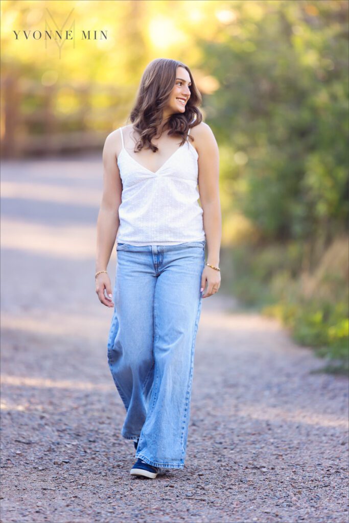 A Legacy High School senior girl walks on a trail during her senior photoshoot with Yvonne Min Photography at South Mesa Trailhead outside Boulder.